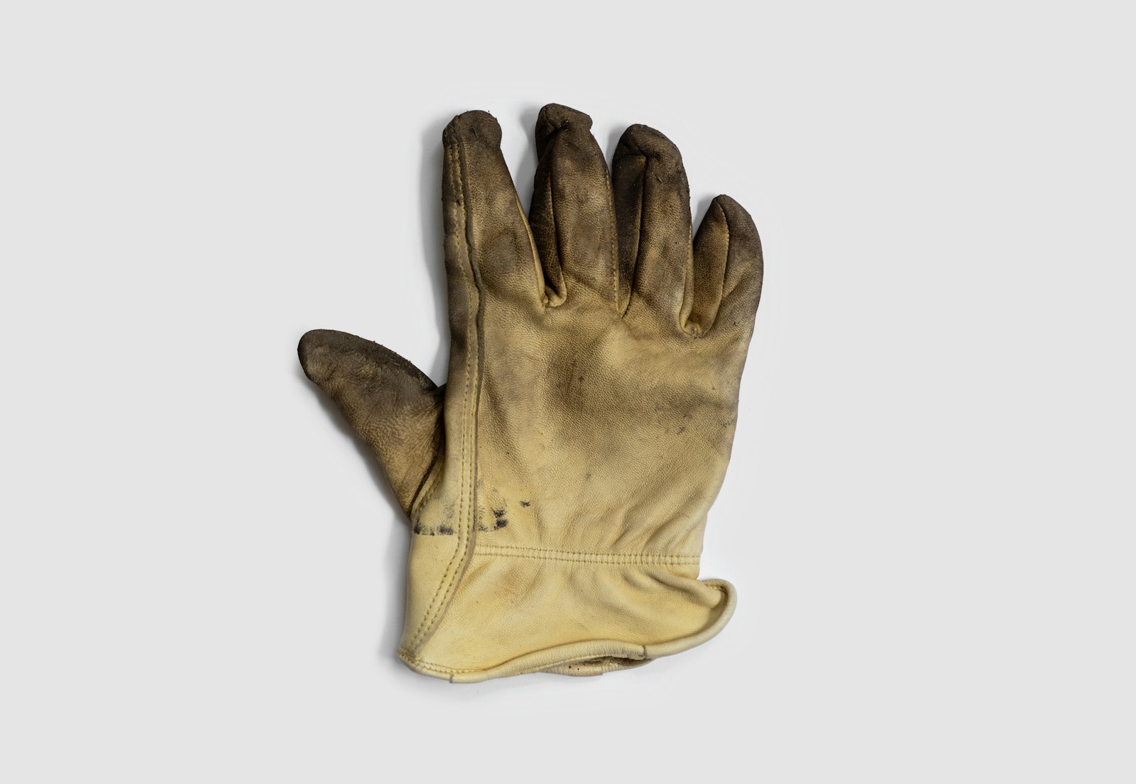 Single worn leather work glove on a pale background