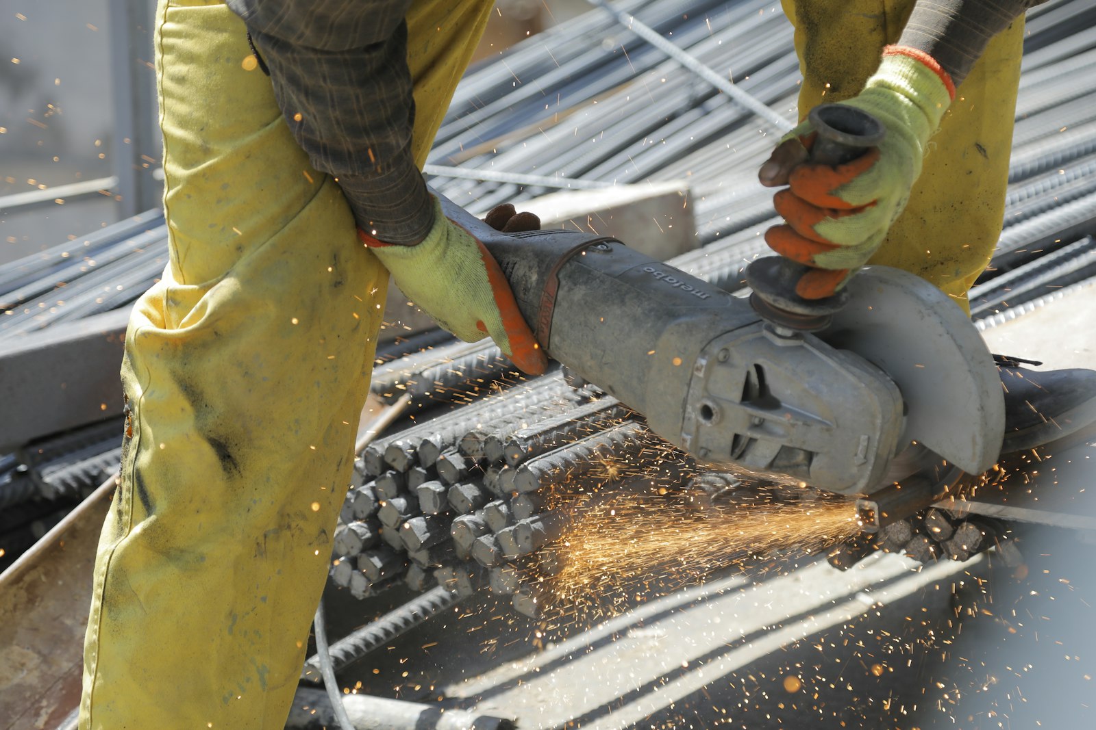 Worker cutting steel with an angle grinder, sparks flying