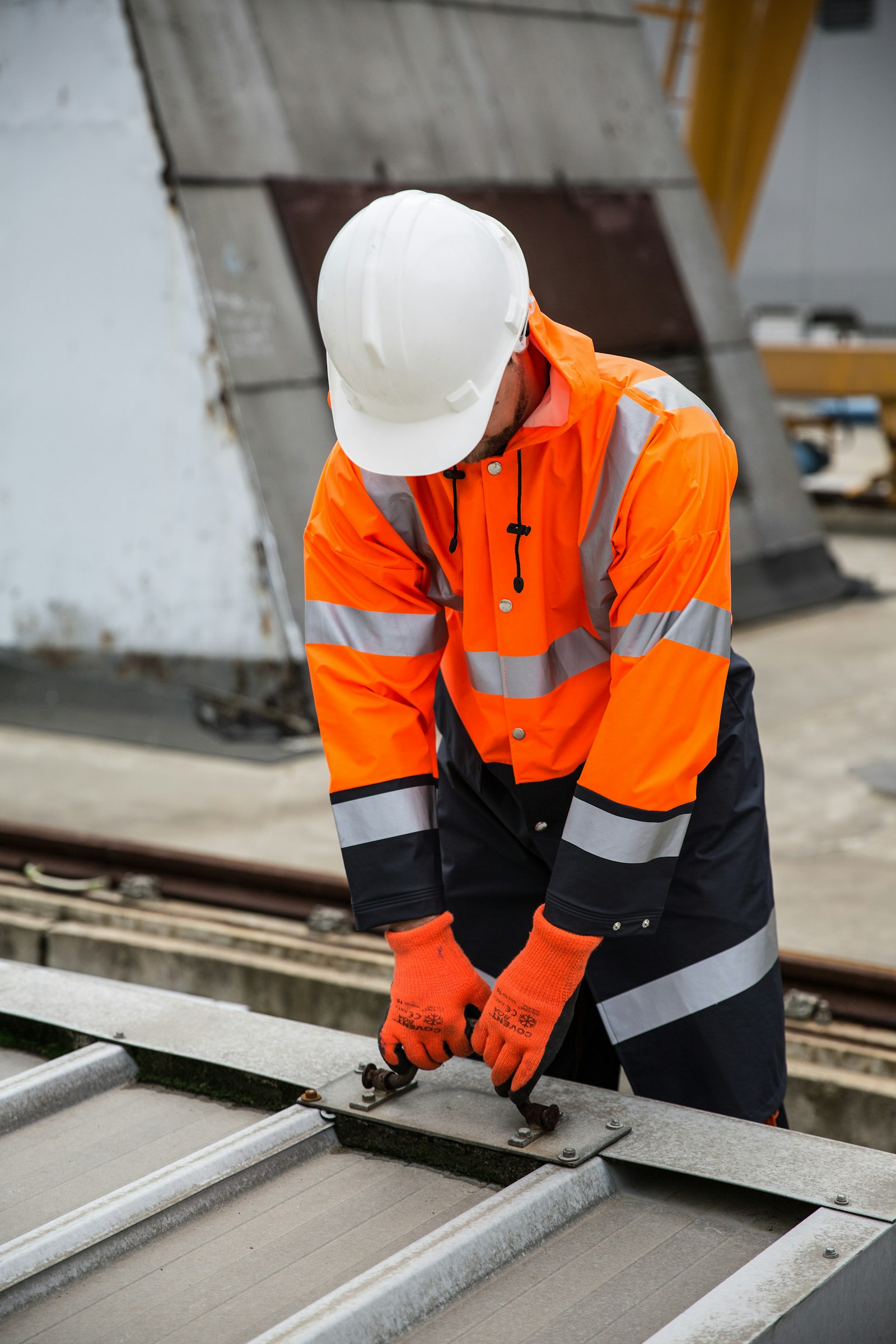 Worker in hi-vis gear handling a rail plate in protective gloves