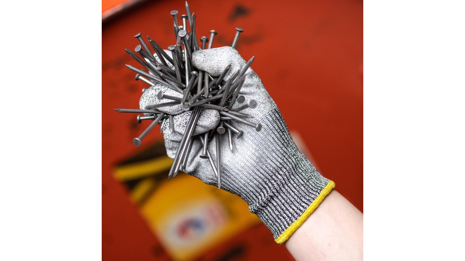 Grey PU-coated HPPE knit glove gripping a bundle of steel nails