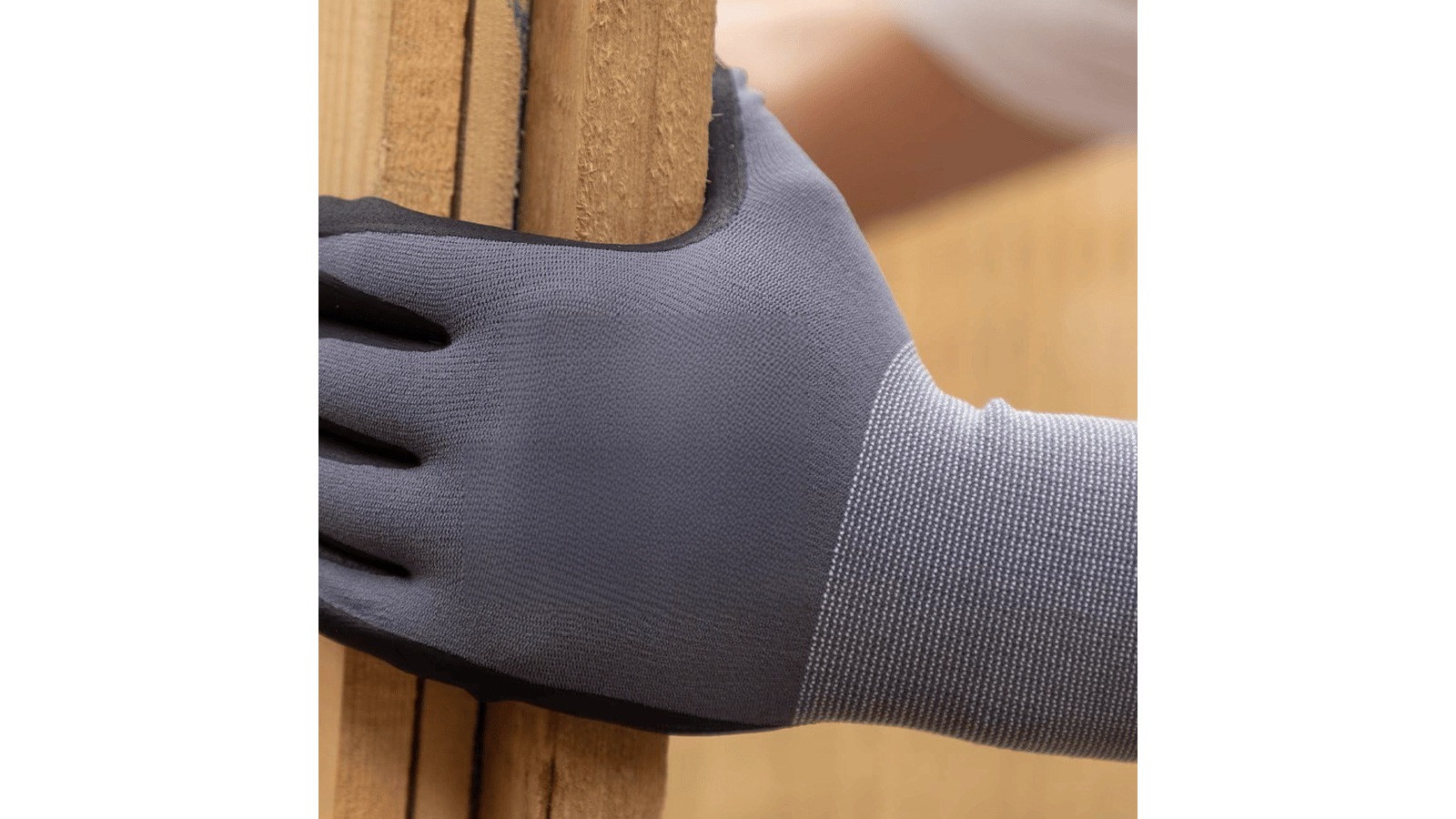 Grey PU-coated knit glove gripping a wooden parcel edge on a bench